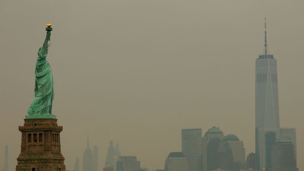 The Statue of Liberty in Jersey City, New Jersey, and the One World Trade Center tower in New York City are seen through a cover of wildfire smoke from New York Harbor, U.S., July 16, 2026. (Reuters/Mike Segar)