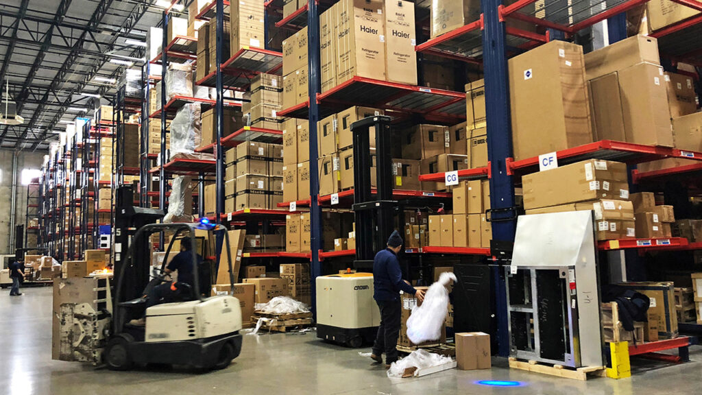 Warehouse workers deal with inventory stacked up to the ceiling at an Electronics Facility