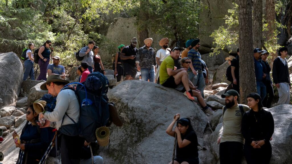 Image of tourist crowded along a trail in Yosemite National Park with some sitting on rocks