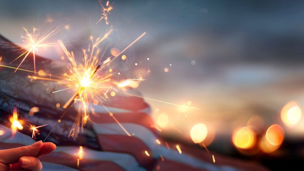Fourth of July composite image with fireworks, American flag, and illuminated sky
