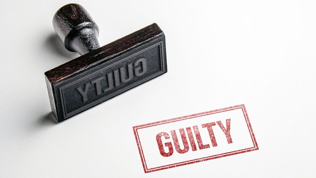Composite image of rubber stamp on its side and the word "Guilty" in red ink against a white background