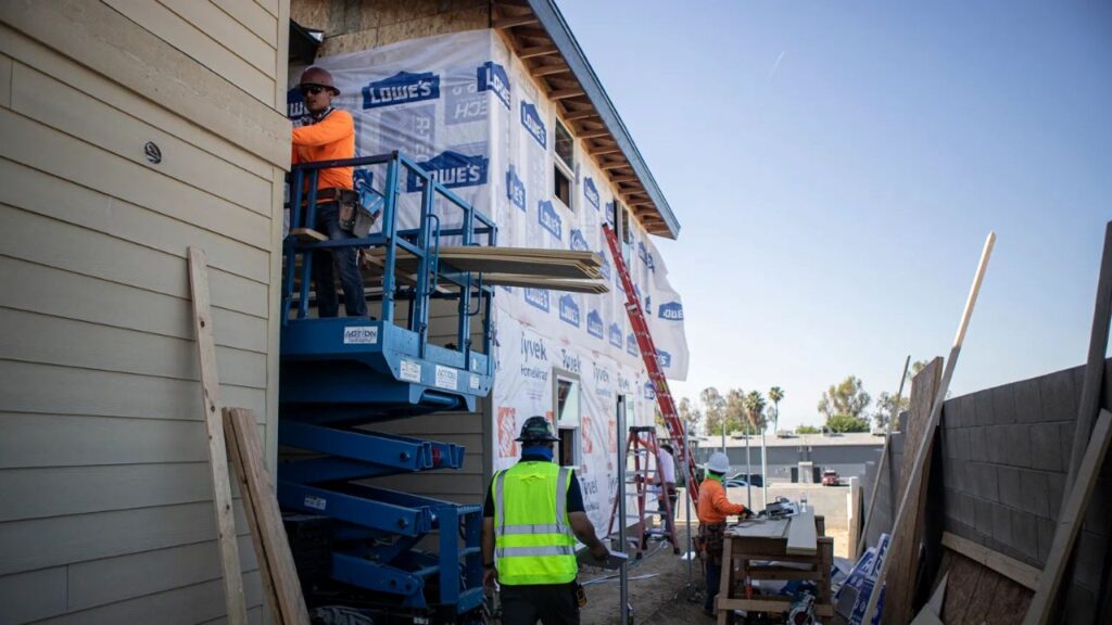 Image if construction workers building affordable housing in Bakersfield, California. Two of the workers are wearing safety orange and another is in a green safety vest