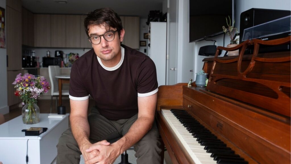 Ellis Ludwig-Leone at his Brooklyn apartment in New York on Aug. 11, 2026. The composers intimated album of nine solo piano pieces, “Quiet Hours,” will be released on Aug. 14, 2026. (James Estrin/ The New York Times)