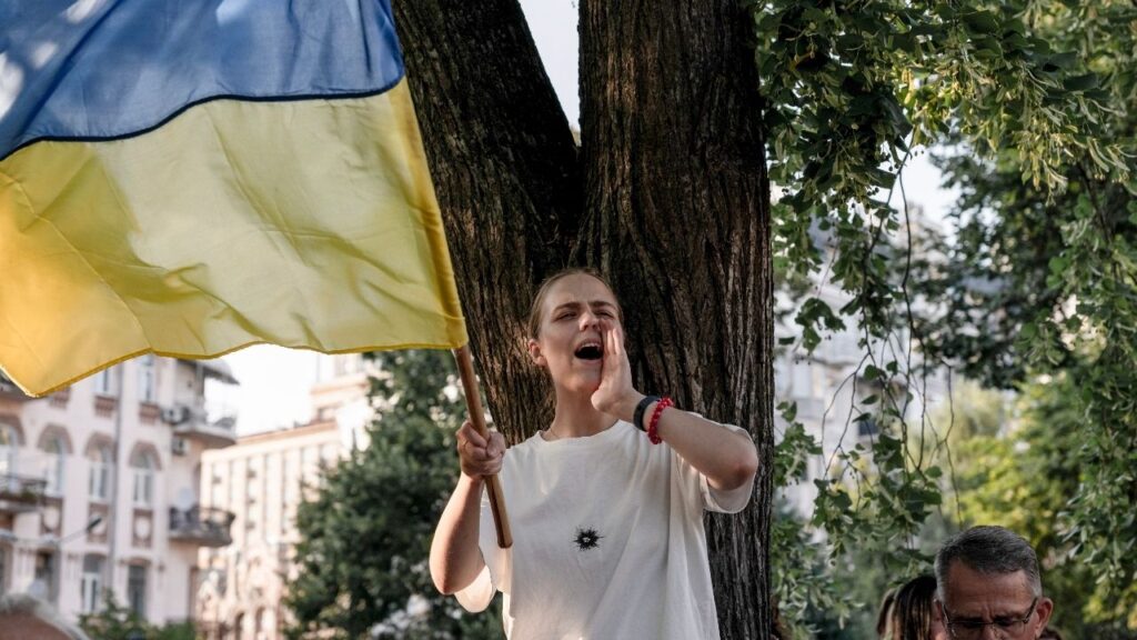 A demonstrator waves the Ukrainian flag as people gather to protest the dismissal of the country’s defense minister, Mykhailo Fedorov, outside the Ivan Franko Theater in Kyiv, Ukraine, on Thursday, July 16, 2026. Fedorov released a video on Aug. 18 calling for wartime elections in Ukraine, setting up a potential confrontation with President Volodymyr Zelenskyy. (Jedrzej Nowicki/The New York Times)
