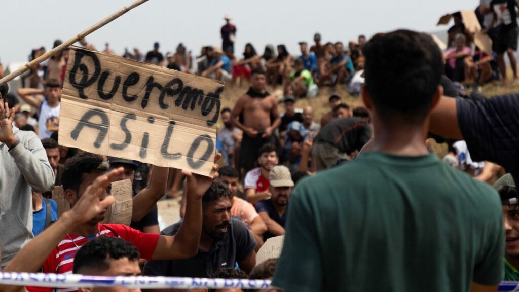 A migrant holds a sign reading "Queremos Asilo," Spanish for "We want asylum," during a gathering in Ceuta, Spain, August 16, 2026. REUTERS/Maria Alejandra Cardona