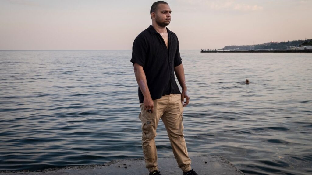Blesson Sebastian stands in the port city of Odesa, Ukraine, Aug. 5, 2026. Sebastian was a second officer on the Golden Leo, a cargo ship that was struck by Russian missiles shortly after departing Odesa on July 19, 2026. He suffered first-degree burns in the attack. (Nicole Tung/The New York Times)