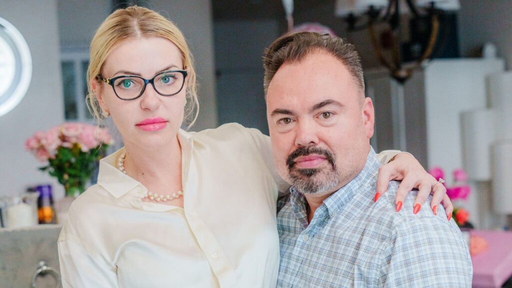Brent Jindra and his wife Galina Bobreneva, a Russian national with a pending application for U.S. residency, at home in Redwood City, Calif., Aug. 5, 2026. Bobreneva, who was detained by ICE for over two weeks and now must wear an ankle monitor, represents a new front in President Donald Trump’s mass deportation drive: arrests at airports of people who have active immigration cases and no criminal history. (Gabriela Bhaskar/The New York Times)