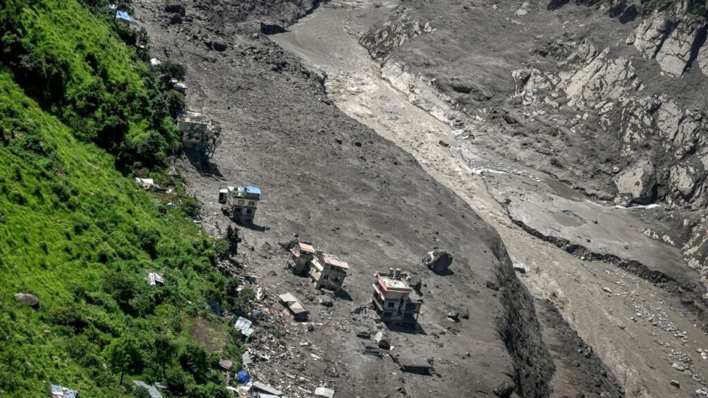 Damaged buildings in a mud line more than 650 feet high after a torrent of water, mud, and ice swept through the Bhotekoshi River in a remote valley in the Rasuwa district, near Nepal’s border with Tibet, on Thursday, Aug. 27, 2026. As emergency workers scoured steep Himalayan valleys on Thursday for survivors of the colossal flash flood in Nepal that killed hundreds, the Nepali and Chinese authorities warned that a second flood might be coming. (Atul Loke/The New York Times)