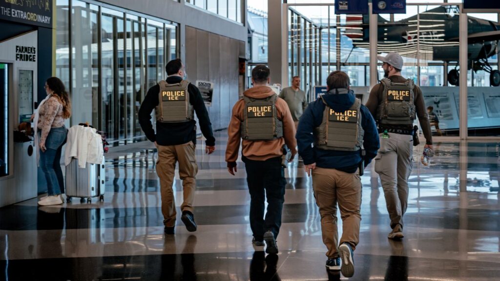 Image of ICE agents walking through an airport lobby