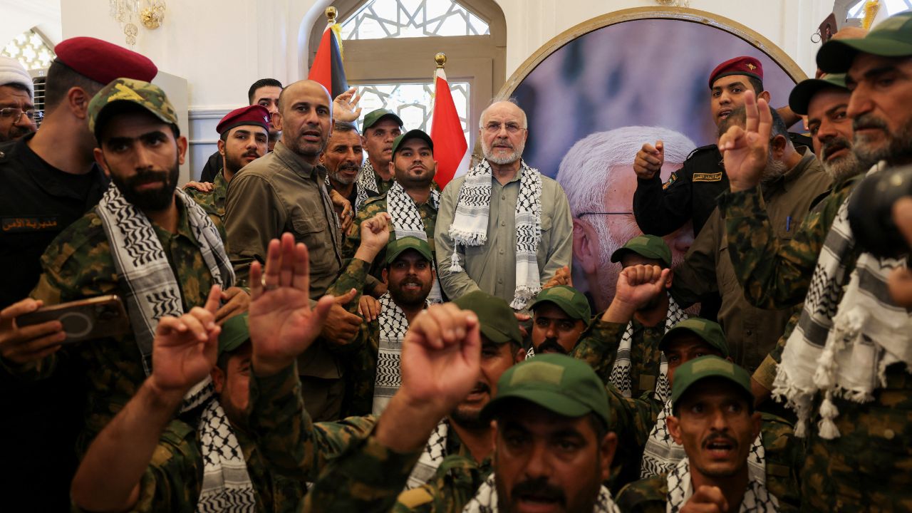 Iranian Parliament Speaker Mohammad Baqer Qalibaf stands with members of Iraq's Popular Mobilization Forces at the grave of Iraqi paramilitary commander Abu Mahdi al-Muhandis, who was killed alongside Iranian military commander Qassem Soleimani in a U.S. drone strike near Baghdad International Airport in January 2020, in Najaf, Iraq, August 21, 2026. (REUTERS/Ahmed Saad)