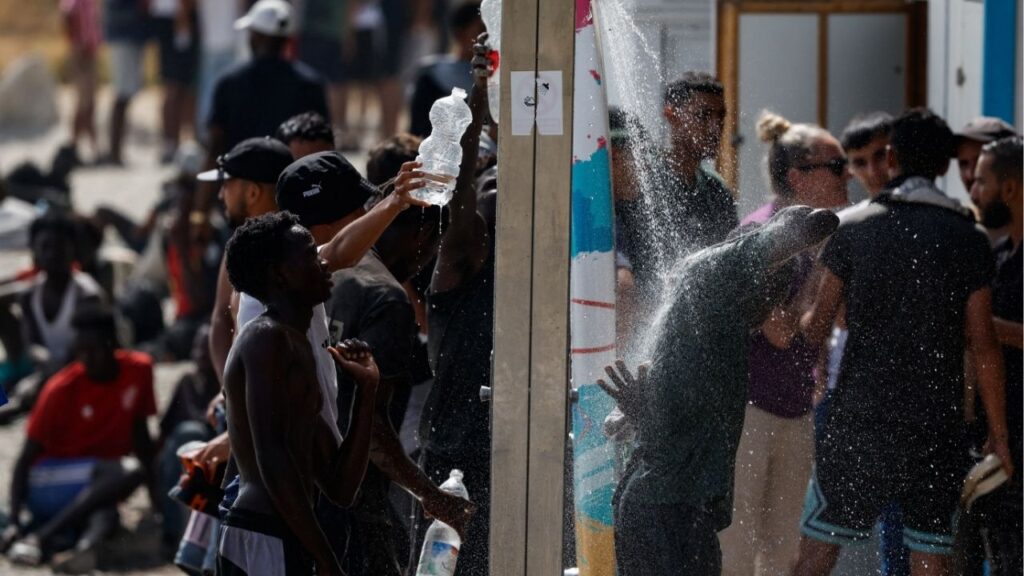 Migrants collect water and cool off as they wait to enter a short-stay migrants centre CETI nearby, following mass crossings of migrants on foot and by sea from Morocco into Spanish territory, in Ceuta, Spain, August 1, 2026. Reuters/Jon Nazca