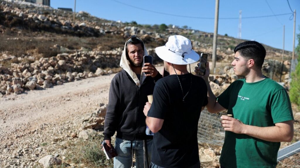 Palestinian-American Loui Ridi and his nephew Ahmed (R), whose house has been encircled by militant settlers for over a week, films an Israeli settler (L) who entered his property in Qusra, Israeli-occupied West Bank, August 18, 2026. REUTERS/Ammar Awad