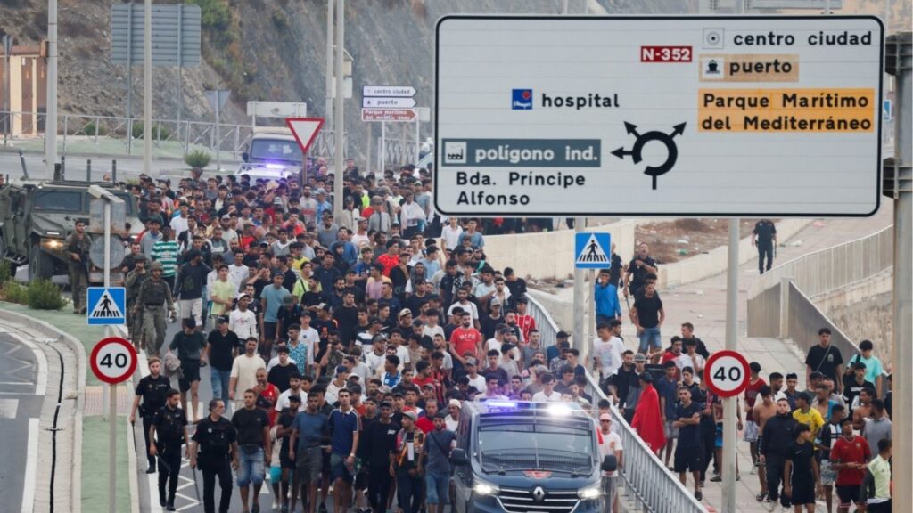 Police officers and Spanish soldiers escort a big group of migrants to the border to take them out of Spain, after mass crossings of migrants on foot and by sea from Morocco into Spanish territory, in Ceuta, Spain, August 1, 2026. Reuters/Jon Nazca