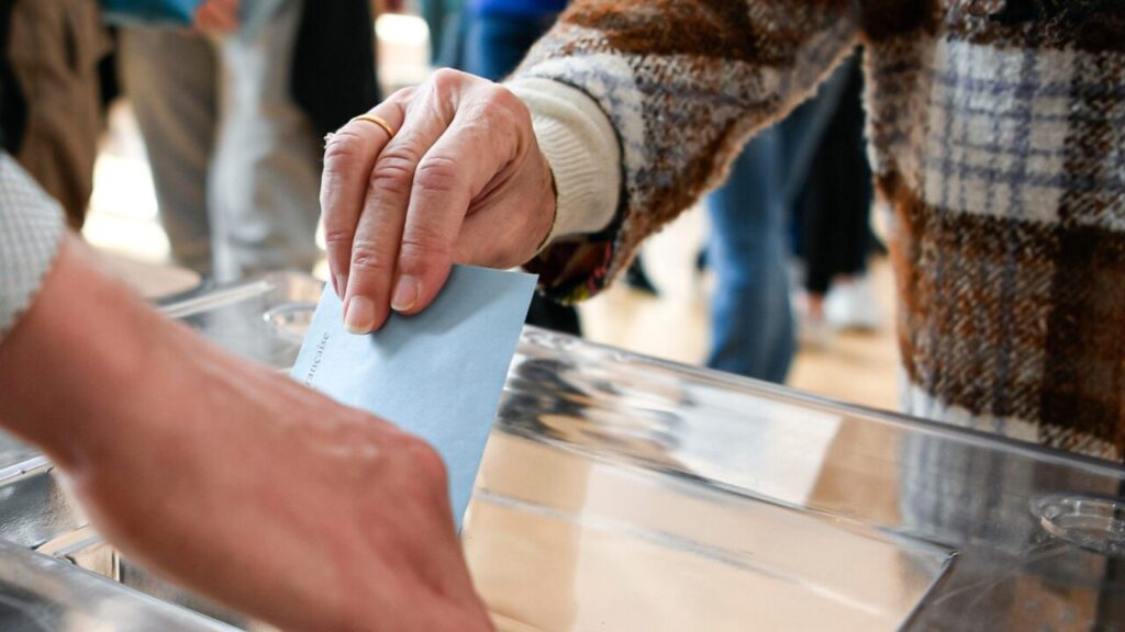 Image of a hand dropping a ballot into a box