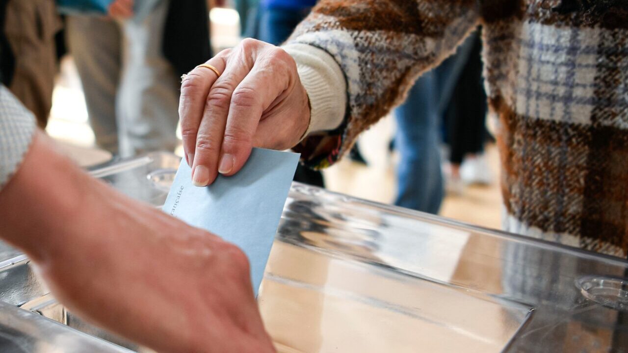 Image of a hand dropping a ballot into a box