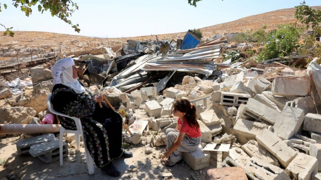 A Palestinian woman and a child sit amid the rubble after Israeli heavy machinery demolished homes in Jinba village in Masafer Yatta, near Hebron, in the Israeli-occupied West Bank, September 23, 2026. REUTERS/Mussa Qawasma