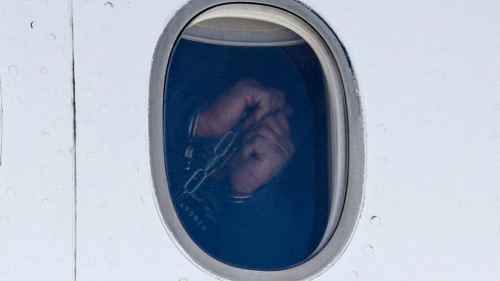 A Venezuelan migrant in handcuffs appears in an aircraft window, as the flight carrying Venezuelan migrants deported from the United States arrives at Simon Bolivar International Airport, in Maiquetia, Venezuela, January 19, 2026. (Reuters File)