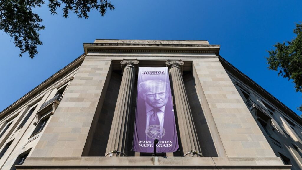 A banner featuring an image of President Donald Trump hangs from the Department of Justice building in Washington, Aug. 13, 2026. A federal judge in Rhode Island ruled on Tuesday, Sept. 29, that the Trump administration had unlawfully sought to withhold funding from more than two dozen domestic violence and sexual assault prevention groups, while using the grants to try to extract political concessions. (Demetrius Freeman/The New York Times)