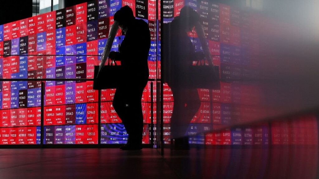 A man walks in front of an electronic screen displaying Japan's Nikkei stock prices quotation board inside a conference hall in Tokyo, Japan, April 27, 2026. REUTERS/Issei Kato