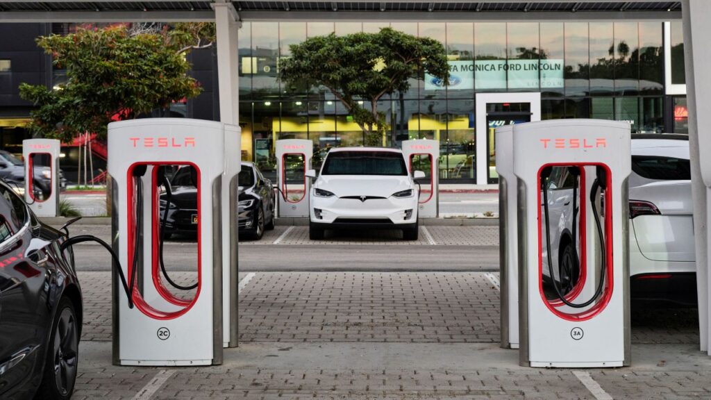 Image of a white Tesla and Tesla EV charging stations