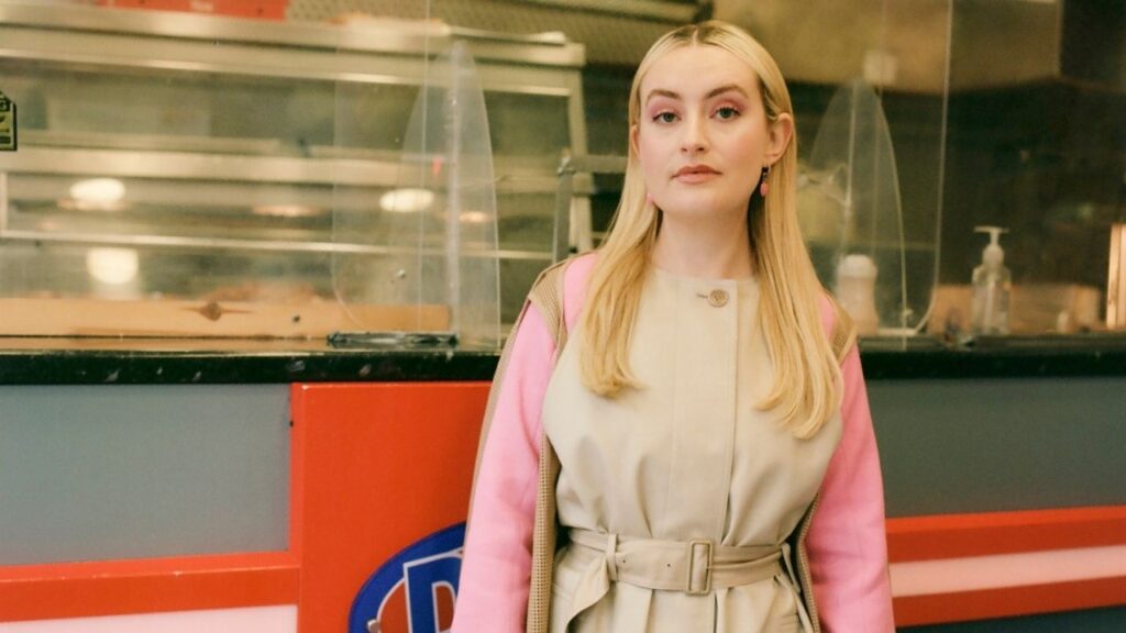 Amelia Dimoldenberg, a comedian and the host of the video series “Chicken Shop Date” on YouTube, at a Dixy Chicken in London, Feb. 2, 2022. After over a decade of flirting with movie stars and athletes while nibbling on fried chicken, Dimoldenberg announced on social media that she would conclude “Chicken Shop Date,” the popular eight-minute YouTube talk show she created. (Charlotte Hadden/The New York Times)