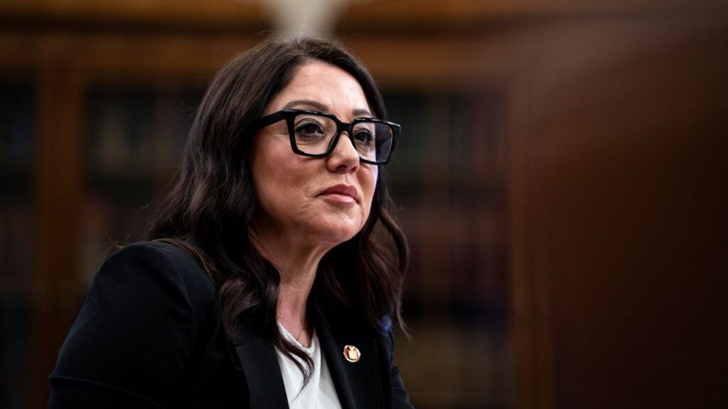 Image of Lori Chavez-DeRemer, in dark jacket and white shirt, wearing glasses, facing right
