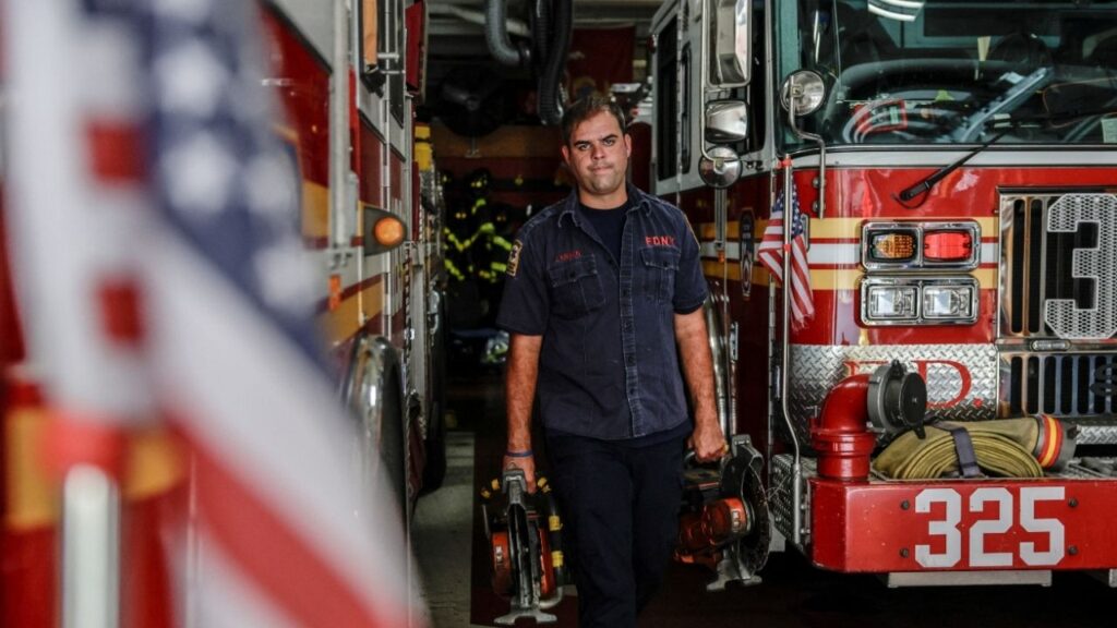 FDNY member Scott Brian Larsen carries equipment at FDNY Engine 325 & Ladder 163, where his father served during the September 11, 2001 attacks, in the Woodside neighbourhood of Queens in New York City, U.S., August 20, 2026. REUTERS/Jeenah Moon