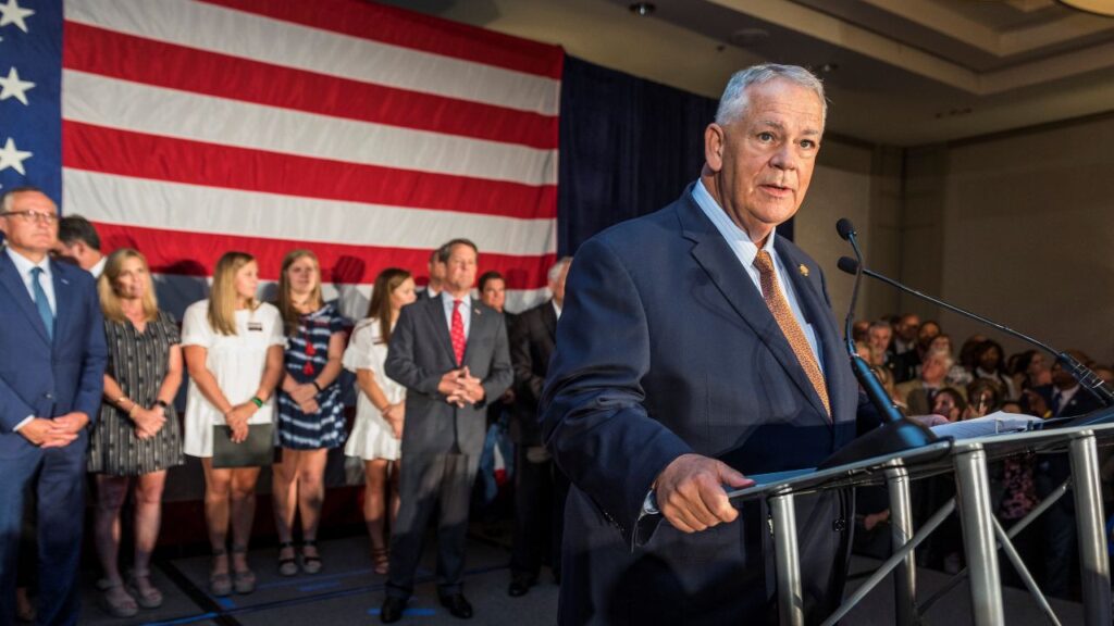 Image of then Georgia Speaker David Ralston in a dark suit facing right and speaking to a crowd from a stage