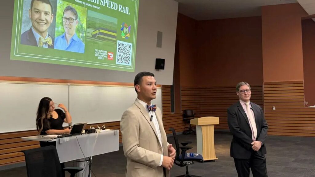 Image of two men standing, facing right, and speaking at a High-Speed Rail town hall