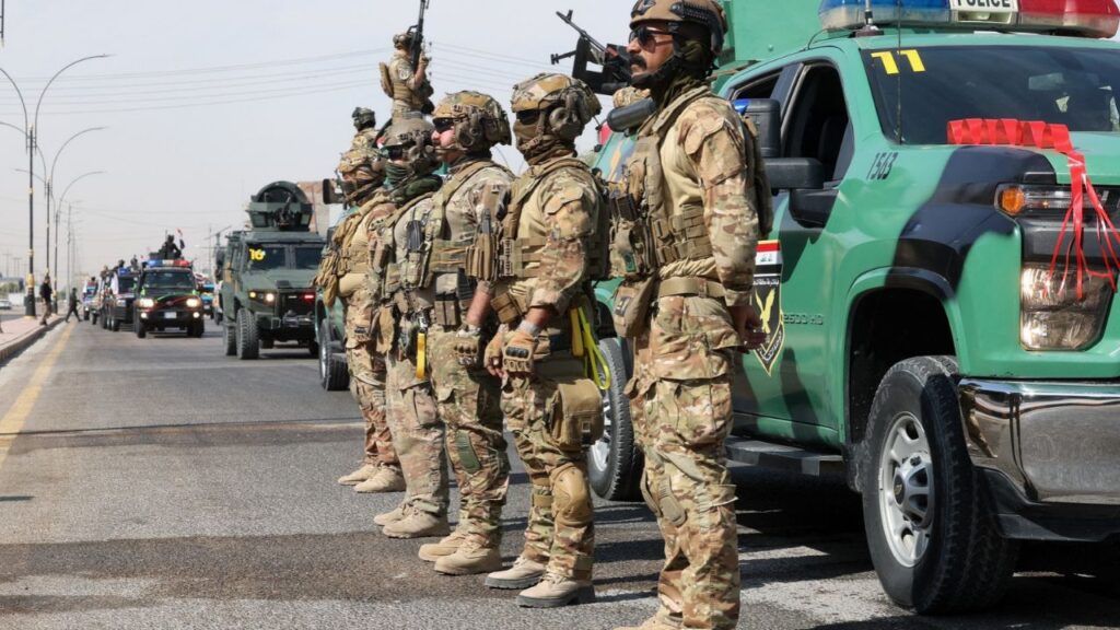 Members of the Iraqi security forces stand next to a convoy moving through the city as they celebrate the withdrawal of US-led coalition forces from Iraq, ending a military presence that began after the 2003 US-led invasion, in Najaf, Iraq, September 30, 2026. REUTERS/Alaa Al-Marjani