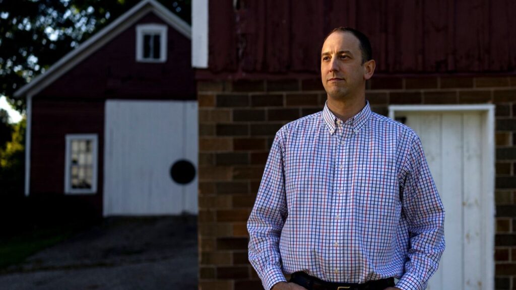John Ebers outside the Michigan Bee Co. barn in Comstock Park, Mich., Sept. 11, 2026. When Ebers was diagnosed with Stage 3 colorectal cancer, he was not given the option of genetic testing, which could have revealed if there were drugs that could attack his cancer. (Emily Elconin/The New York Times)