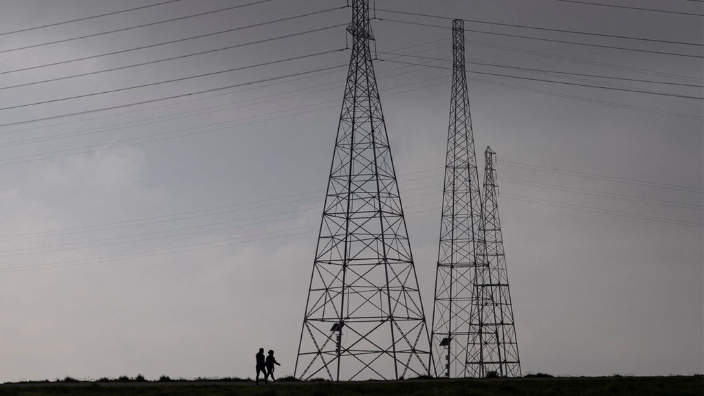 Residents walk by power grid towers at Bair Island State Marine Park in Redwood City, California, United States, January 26, 2022. (Reuters/Carlos Barria)