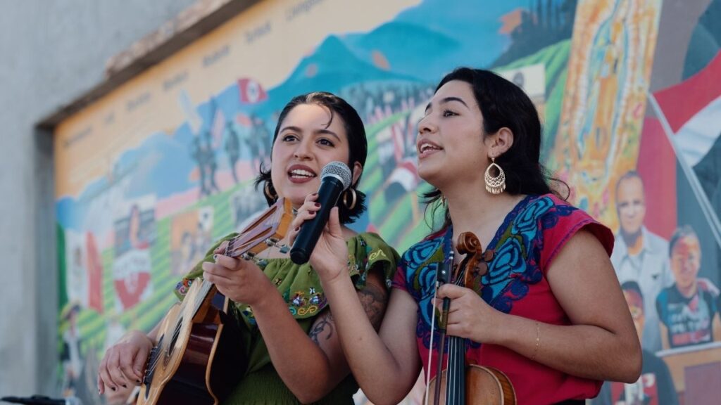 Sisters Xóchitl (left) and Anaí Morales of Los Morales singing in Poplar for Larry Itliong Day. (Photo courtesy of the artists)