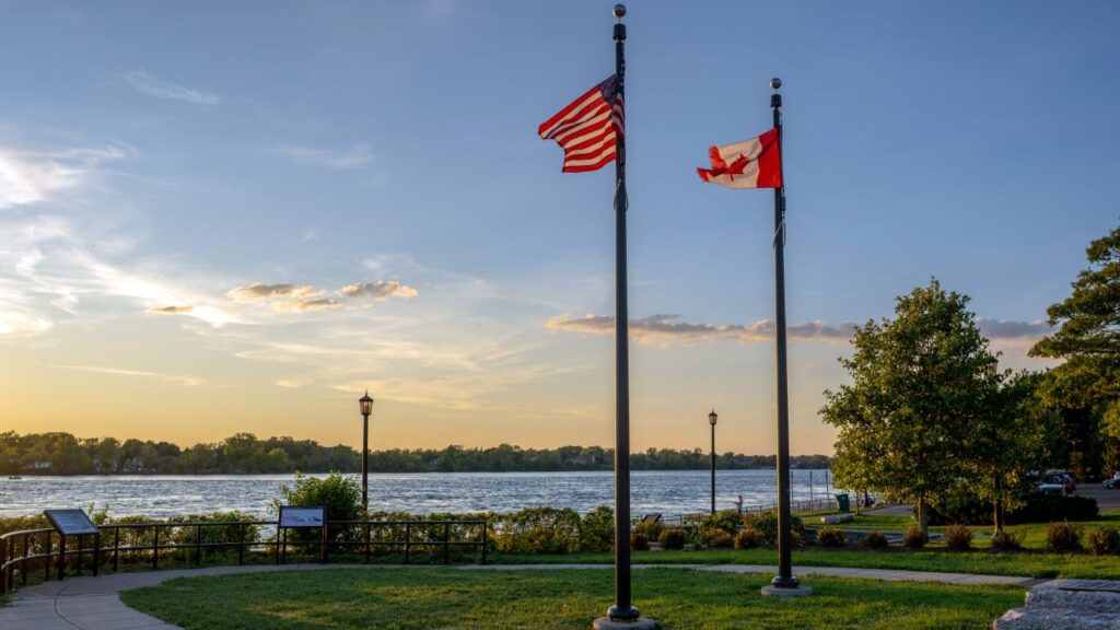Image of the U.S. and Canadian flags flapping in the wind near the Peace Bridge