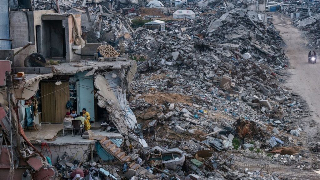 Tamer Hassan al-Shafei and his family sit for an evening meal during Ramadan in the remains of their home, overlooking the ruins of Beit Lahiya in the Gaza Strip, March 4, 2025. The film “NAZA” investigates the killing of Palestinians by Israeli forces in Gaza — Israel’s culture minister has suggested revoking the directors’ citizenship. (Saher Alghorra/The New York Times)