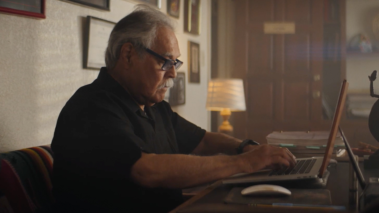 Image of director Luis Valdez sitting on a couch and facing left