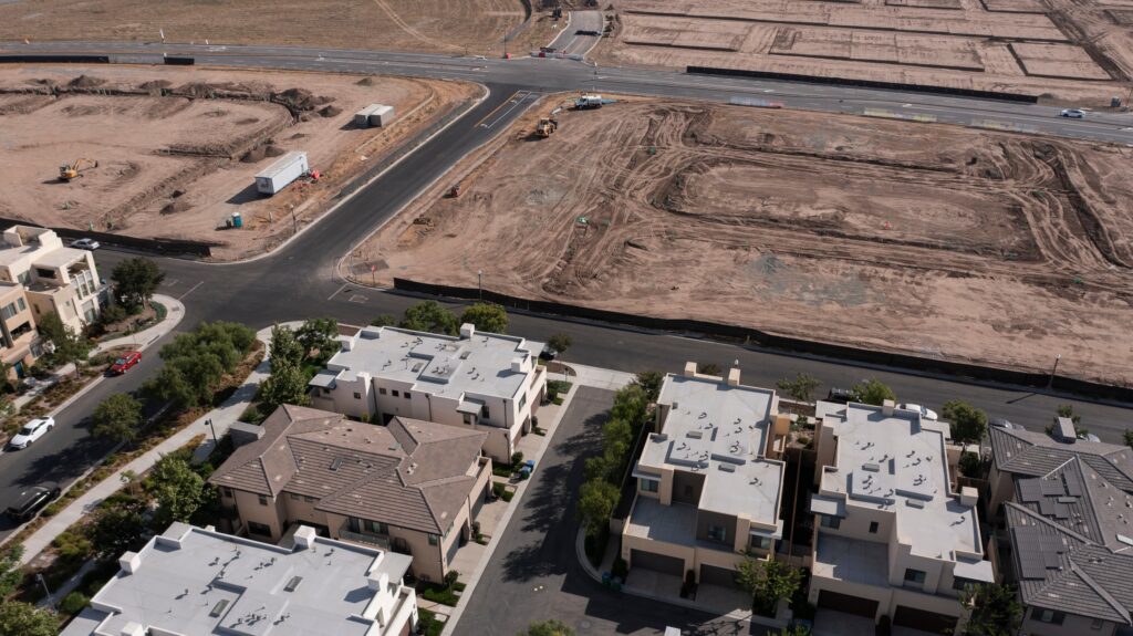 Aerial view of a housing development under construction and adjacent empty graded lots