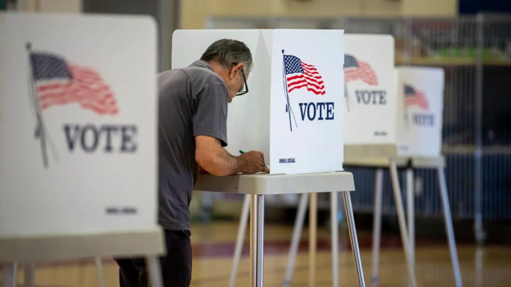 Image of a voter filling out a ballot in a school gymnasium