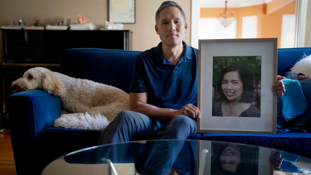 Image of man holding a portrait of his wife, who was killed in an accident caused by a big-rig driver in California