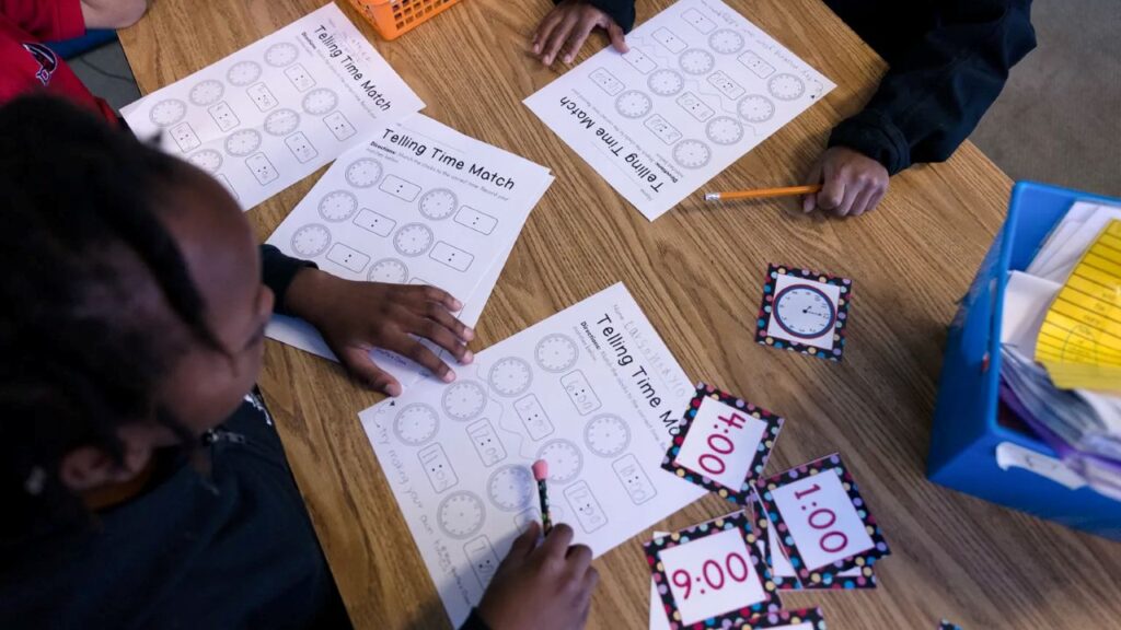 Overhead view of students sitting at a table and learning how to tell time