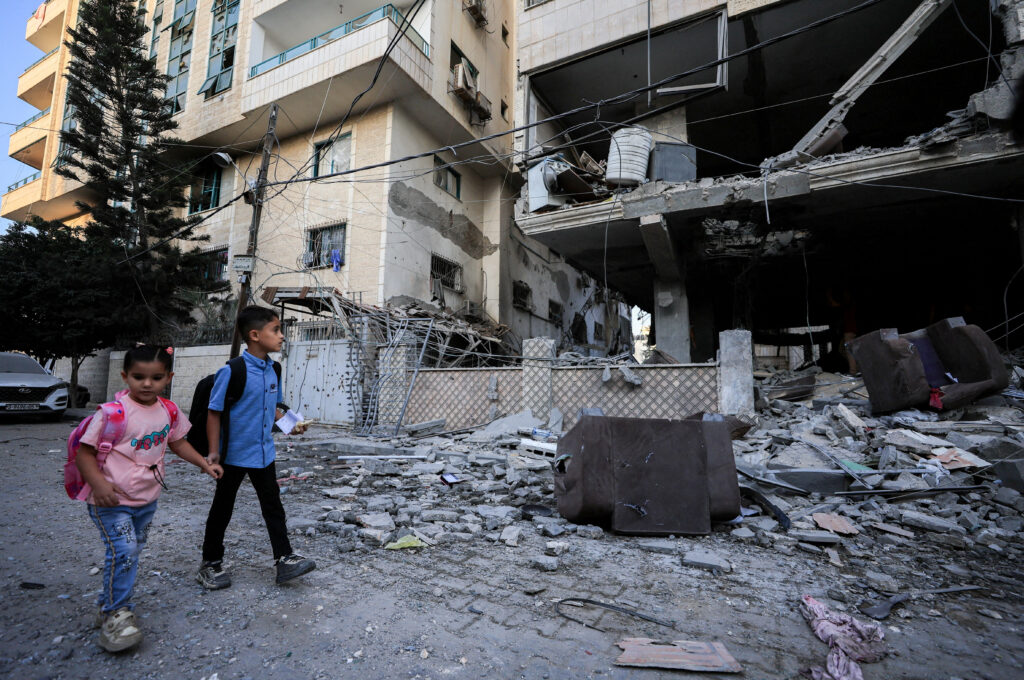 Palestinian children walk past the site of an Israeli strike on an apartment building in Gaza City, October 3, 2026. Reuters/Dawoud Abu Alkas