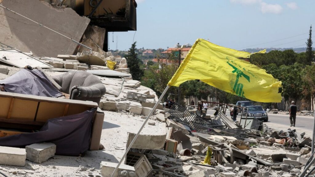 A Hezbollah flag flutters amid rubble of destroyed buildings, in Deir Qanoun al-Nahr, Tyre district, southern Lebanon, June 15, 2026. REUTERS/Aziz Taher
