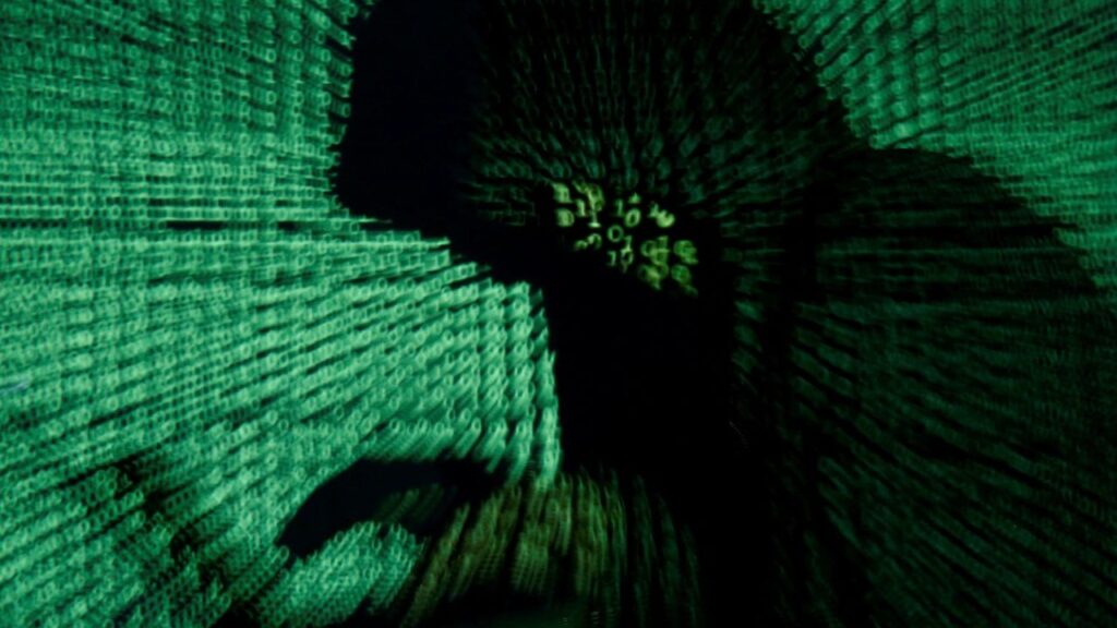 A man holds a laptop computer as cyber code is projected on him in this illustration picture taken on May 13, 2017. (Reuters File)