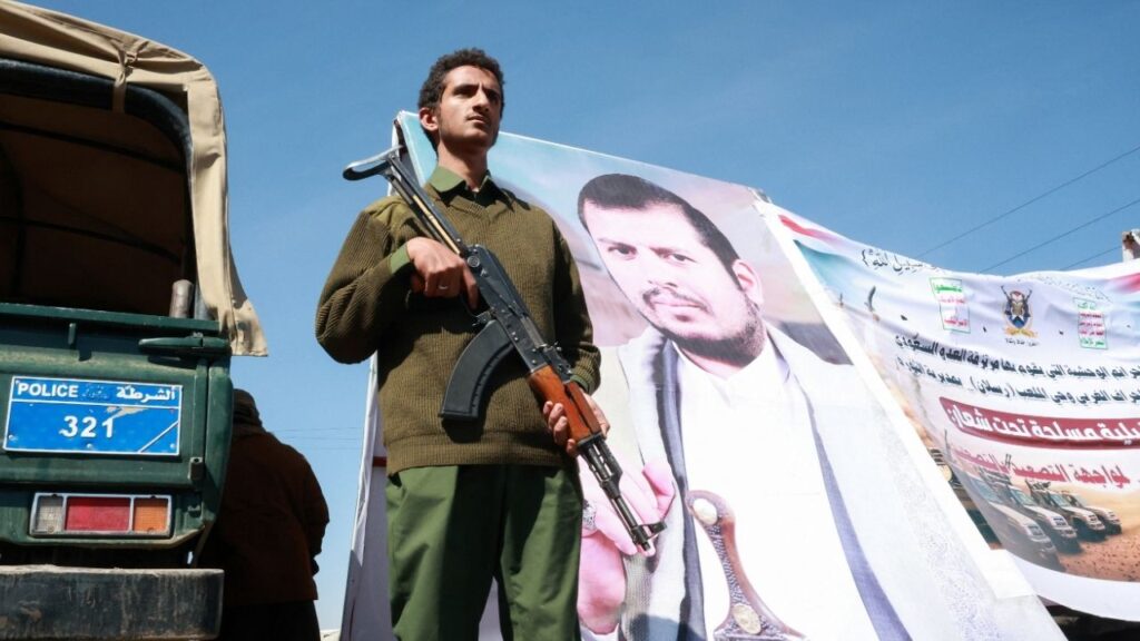 A member of Houthi security forces stands next to a poster of Houthi leader Abdul-Malik al-Houthi at the site of a gathering of Houthi supporters to show solidarity with the movement as fighting intensifies across several fronts, in Sanaa, Yemen October 7, 2026. REUTERS/Mohammed al-Mahdi