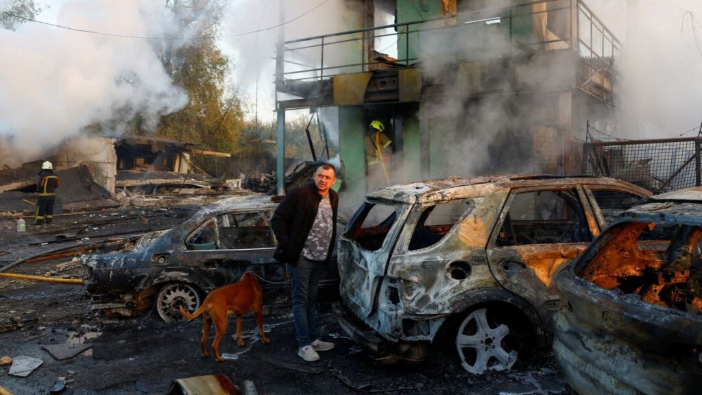 A resident with a dog looks on at the site of private car garages hit by a Russian missile strike, amid Russia's attack on Ukraine, in Kyiv, Ukraine October 7, 2026. (REUTERS/Valentyn Ogirenko)