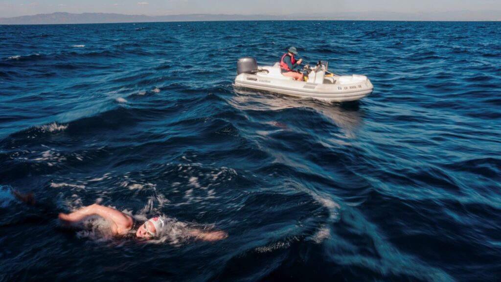 Image of a woman swimming in the Pacific Ocean alongside an inflatable boat