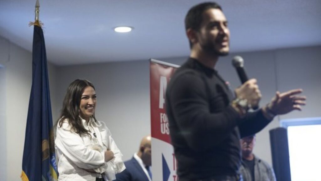 Rep. Alexandria Ocasio-Cortez (D-N.Y.) watches Dr. Abdul El-Sayed, the Democratic nominee for Senate in Michigan, speak during a campaign event in Iron Mountain, Mich., on Thursday, Oct. 15, 2026. Ocasio-Cortez on Friday transferred $1 million to a political account to help elect El-Sayed. “I’m not waking up on November 4th wishing I did more to combat the smears aimed at Abdul,” she said in a statement. (Zbigniew Bzdak/The New York Times)