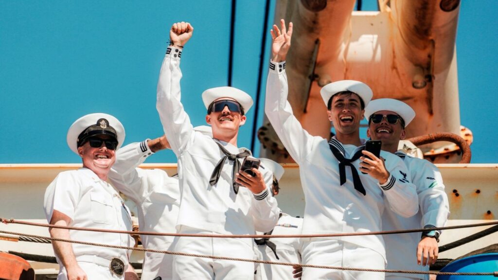 Sailors wave as the aircraft carrier USS Abraham Lincoln arrives at Naval Air Station North Island in San Diego, Calif., on Thursday, Oct. 8, 2026. The carrier, whose crew endured food shortages and mental health struggles prompted by a near-record 322-day deployment in support of the Iran war, returned on Thursday to its home port of San Diego. (Gabriela Bhaskar/The New York Times)