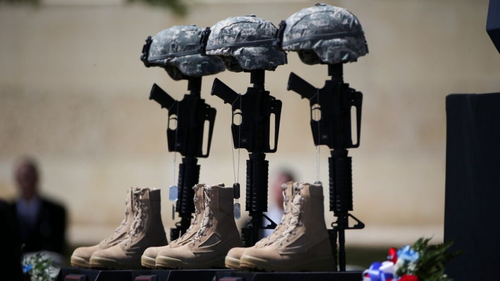 Image of three guns topped by helmets with military boots below in honor of gunned down soldiers