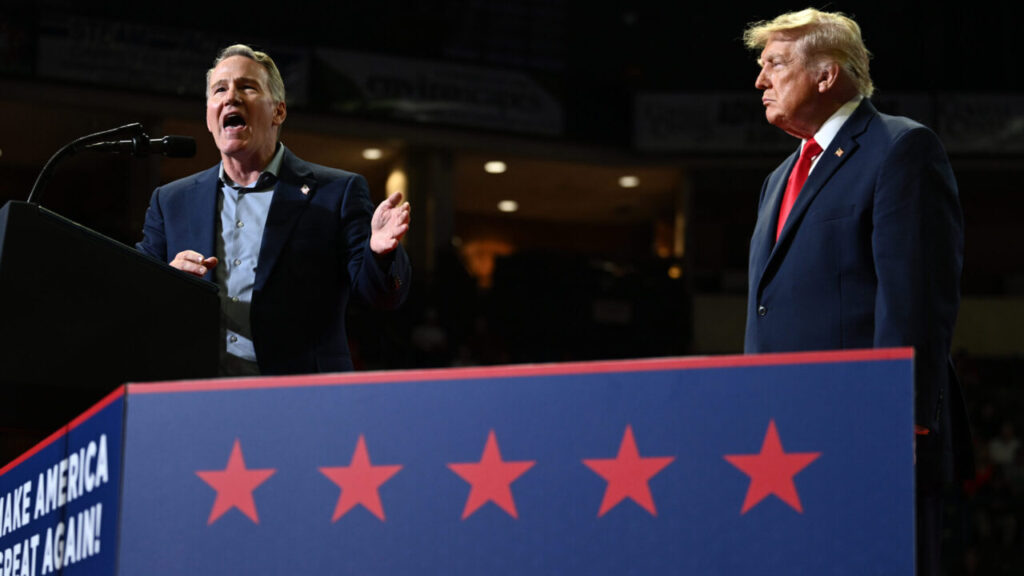 Image of President Trump and Sen. John Husted, both in blue suits, on a raised platform